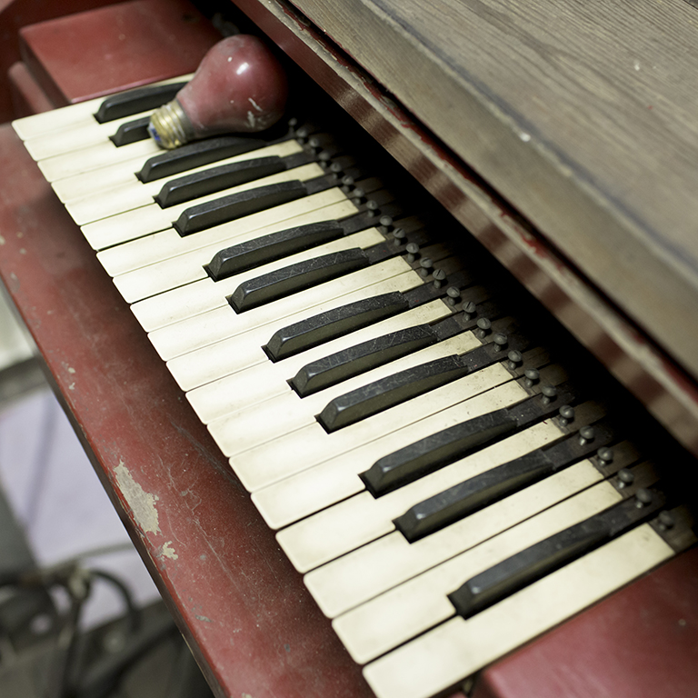 A red lightbulb sits on the keys of a calliope being restored